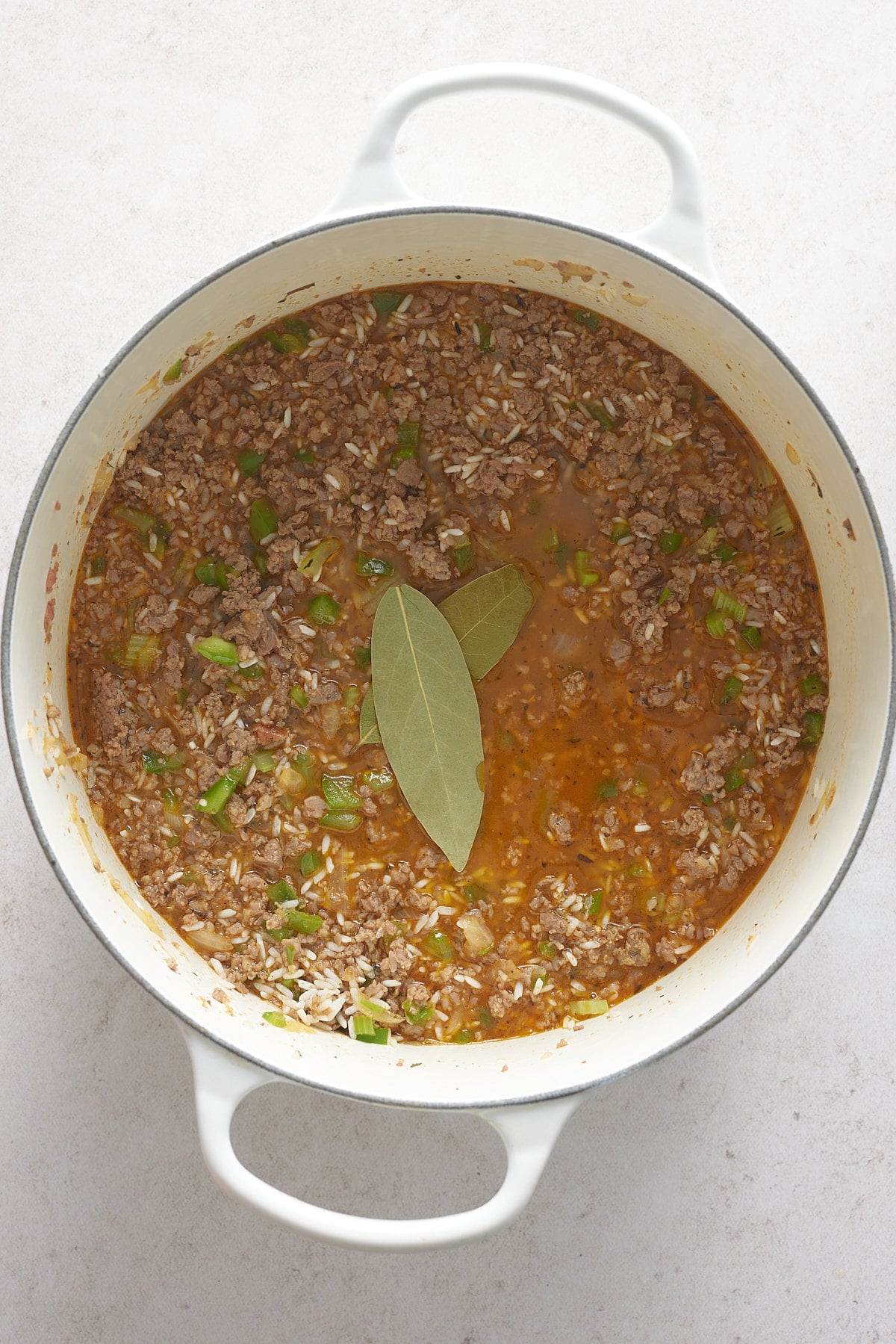 large pot with rice, broth, meat and bay leaf