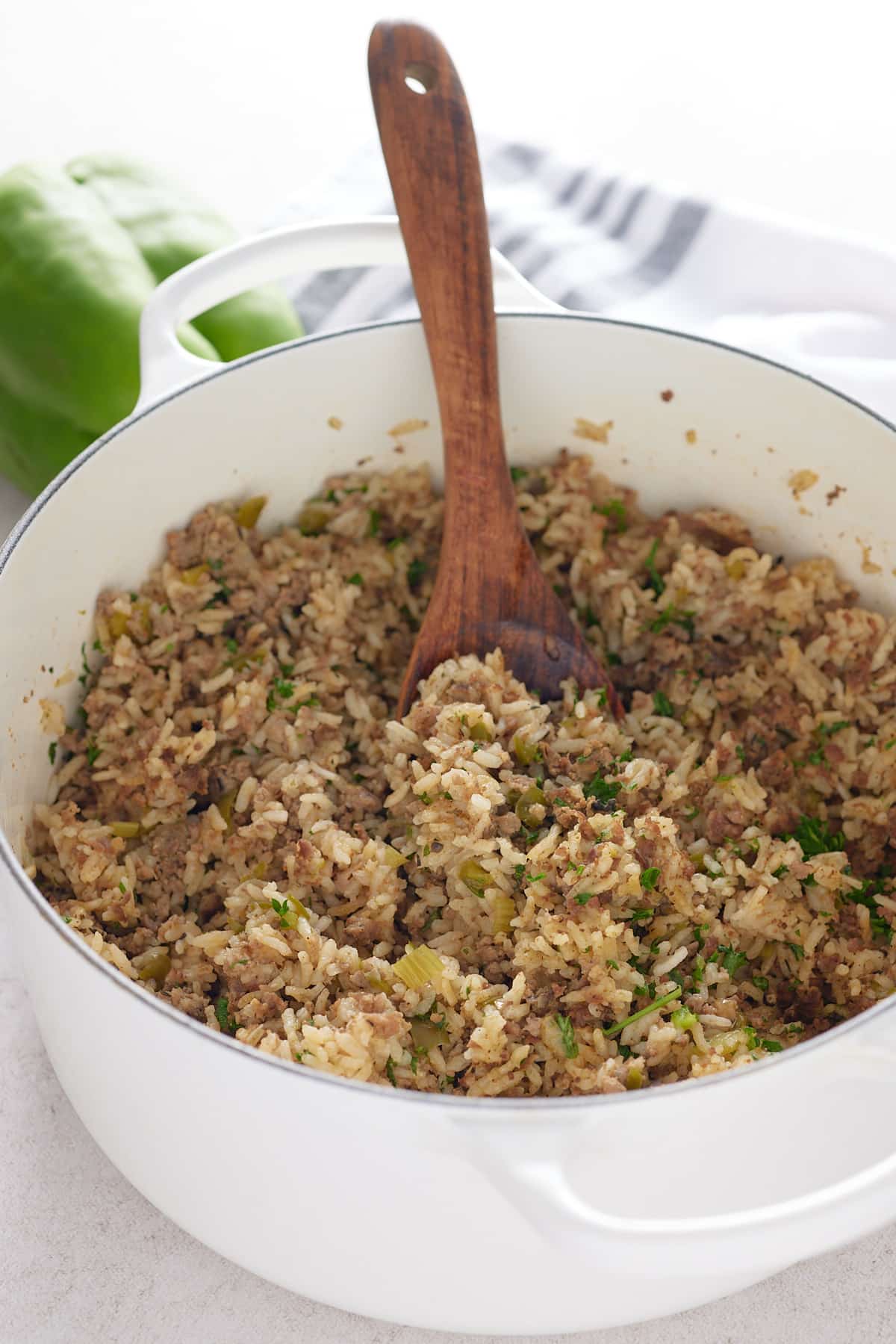 white pot of dirty rice with wooden spoon