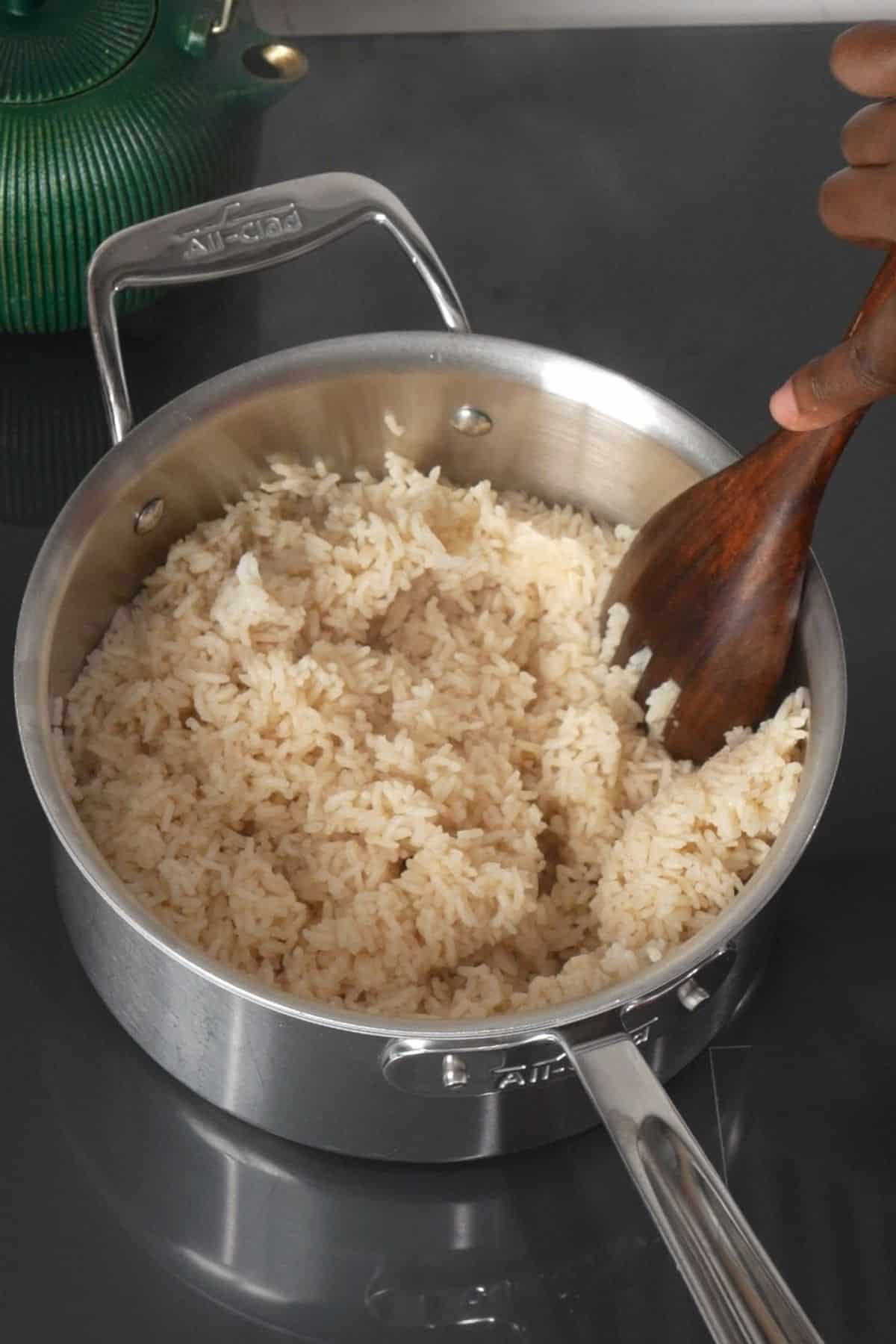 cooked rice being fluffed in pot