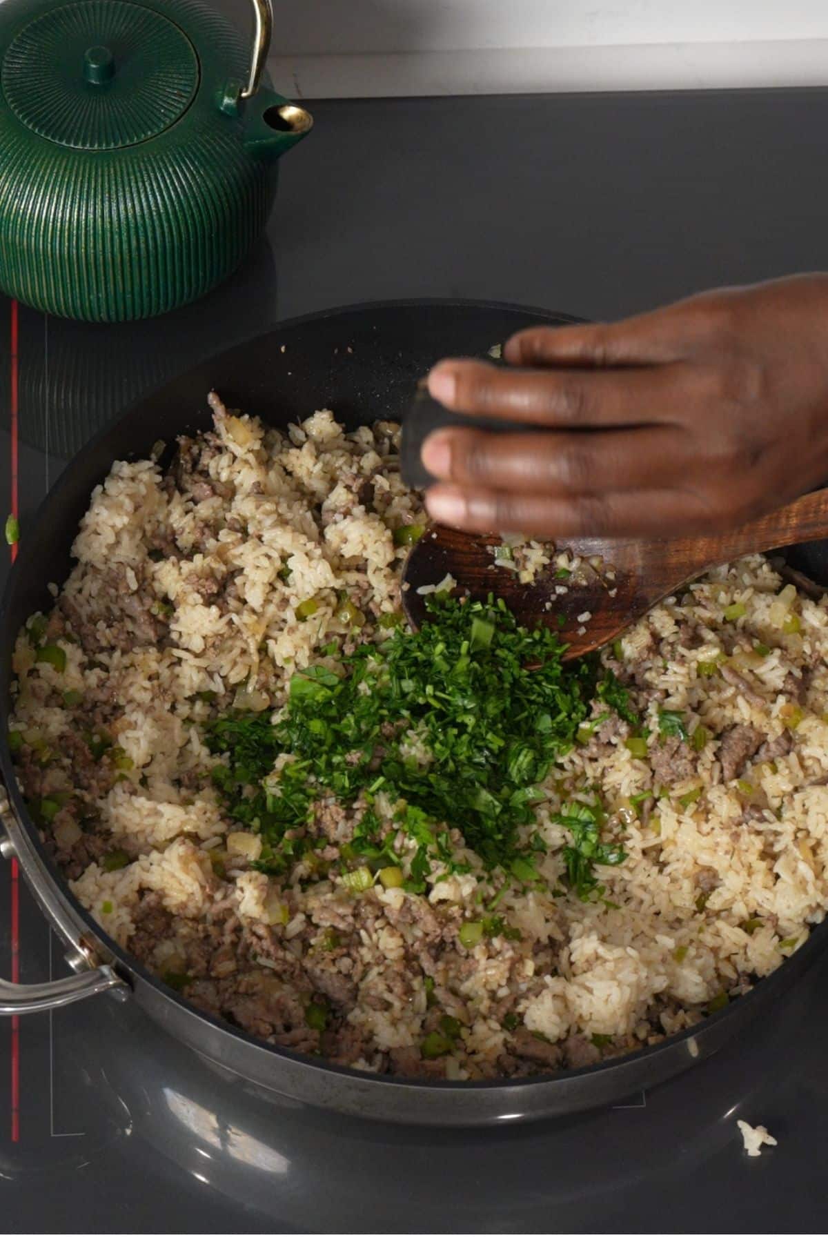 parsley being added to the brown meat in skillet