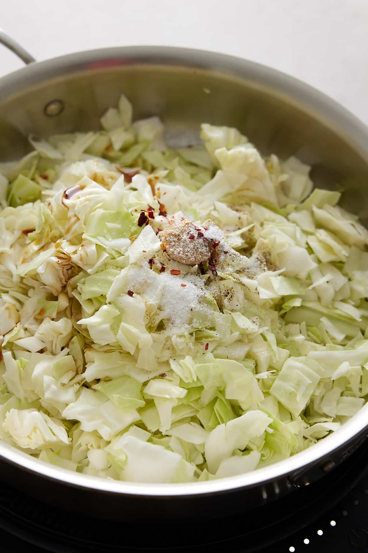 spices added to the top of the shredded cabbage in the pan