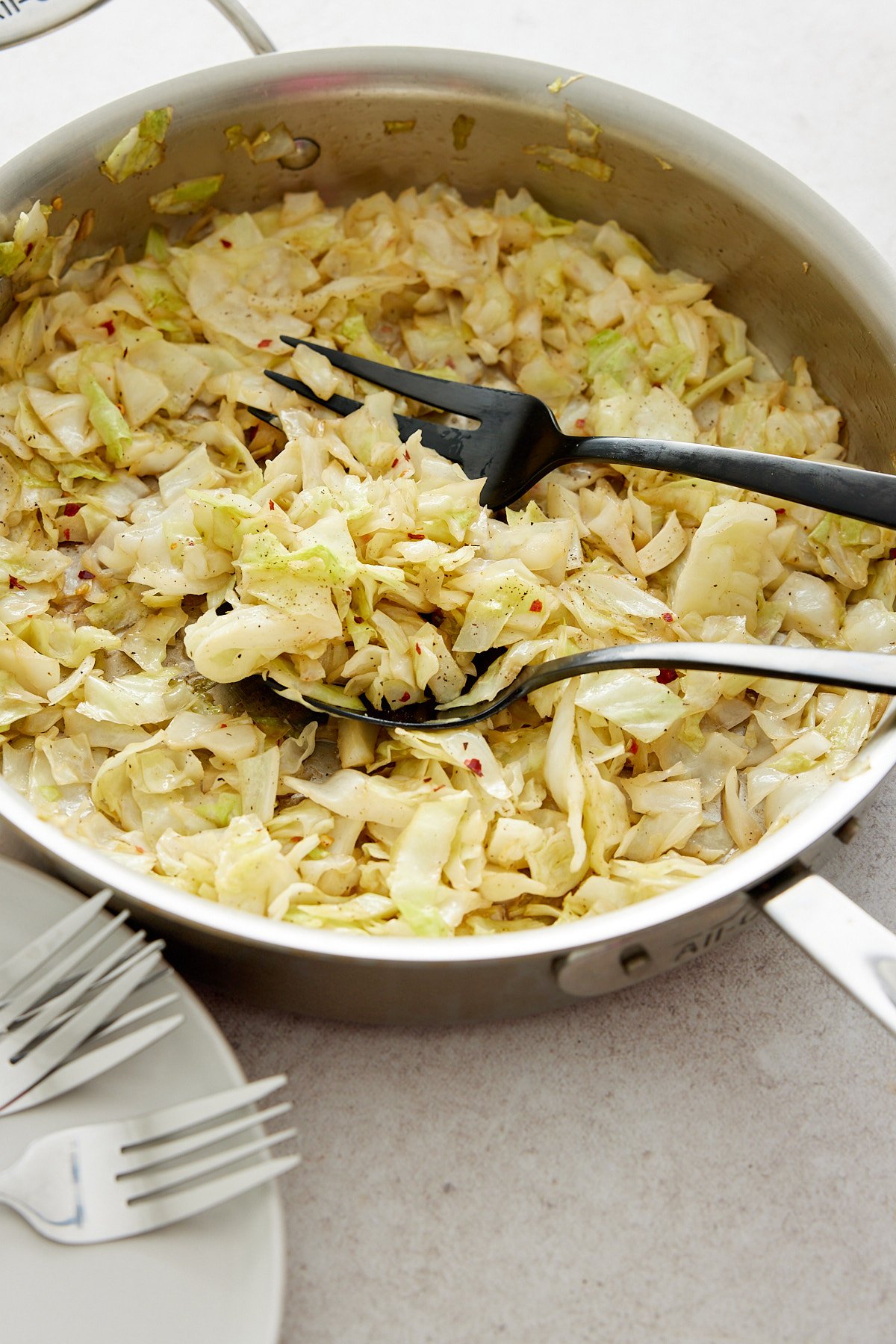 serving fork and spoon in a pan of fried cabbage