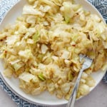 overhead view of cabbage on a white plate with a fork next to a blue napkin