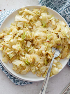 overhead view of cabbage on a white plate with a fork next to a blue napkin