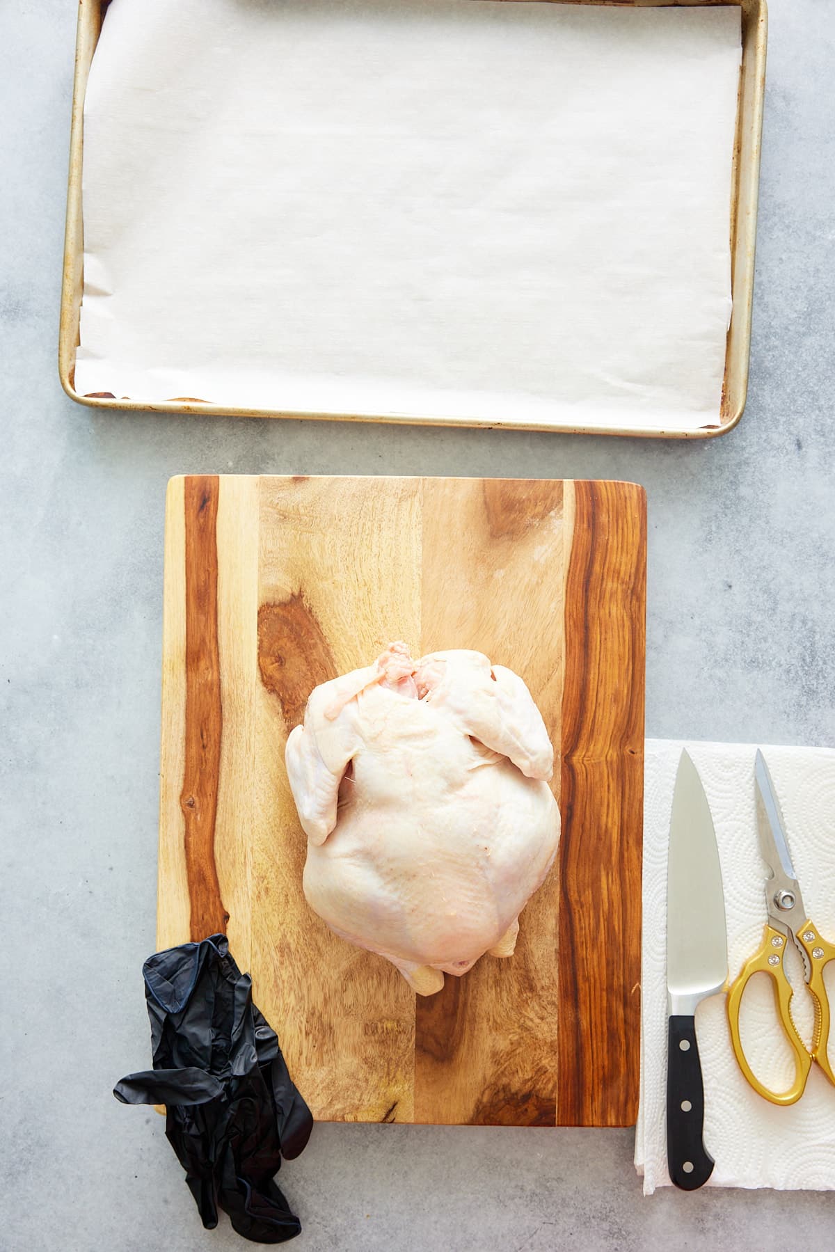raw chicken and tools needed to cut the chicken, like gloves, knife, kitchen shears