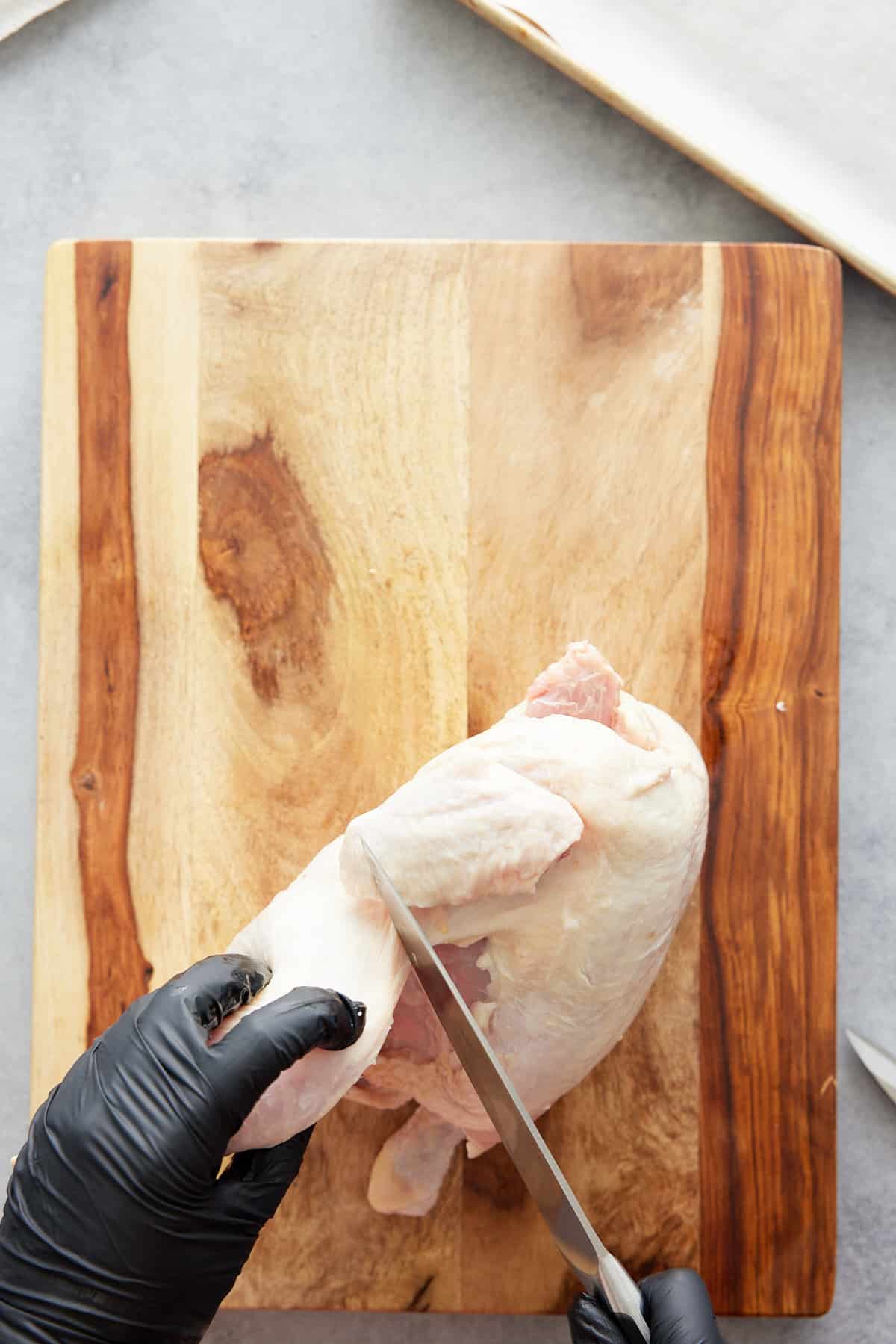 hand cutting chicken leg from chicken body