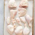 raw cut up chicken pieces on parchment paper