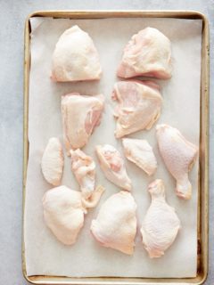 raw cut up chicken pieces on parchment paper