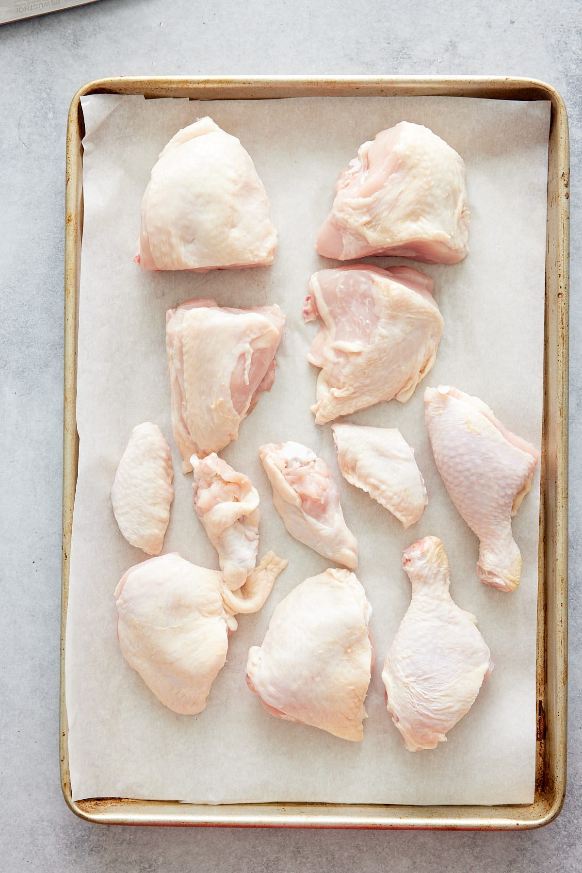 raw cut up chicken pieces on parchment paper