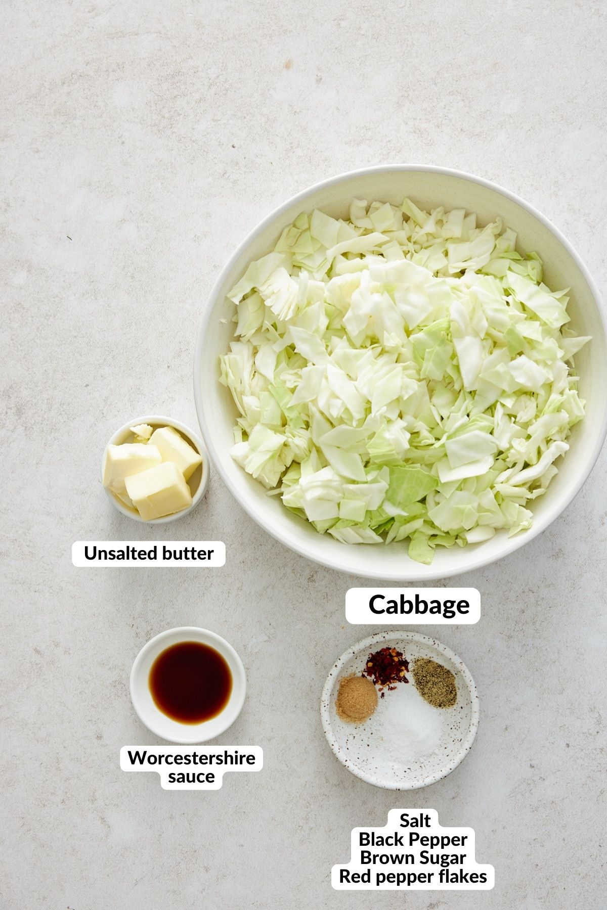 ingredients with labels for fried cabbage recipe in small white bowls on a white background