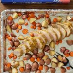 mustard glazed pork tenderloin and potatoes and carrots on sheet pan lined with foil