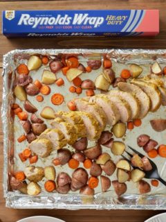 mustard glazed pork tenderloin and potatoes and carrots on sheet pan lined with foil