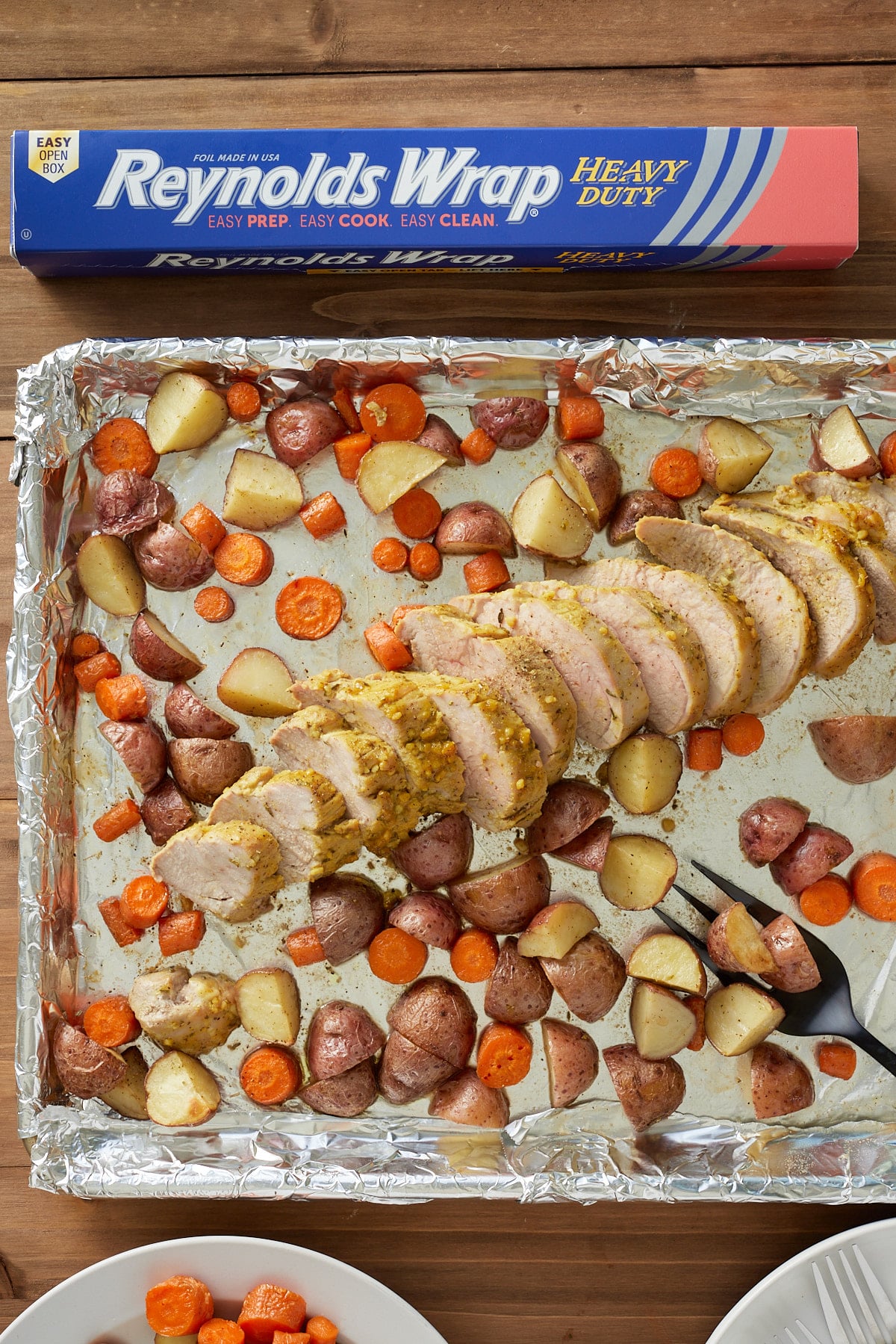 mustard glazed pork tenderloin and potatoes and carrots on sheet pan lined with foil
