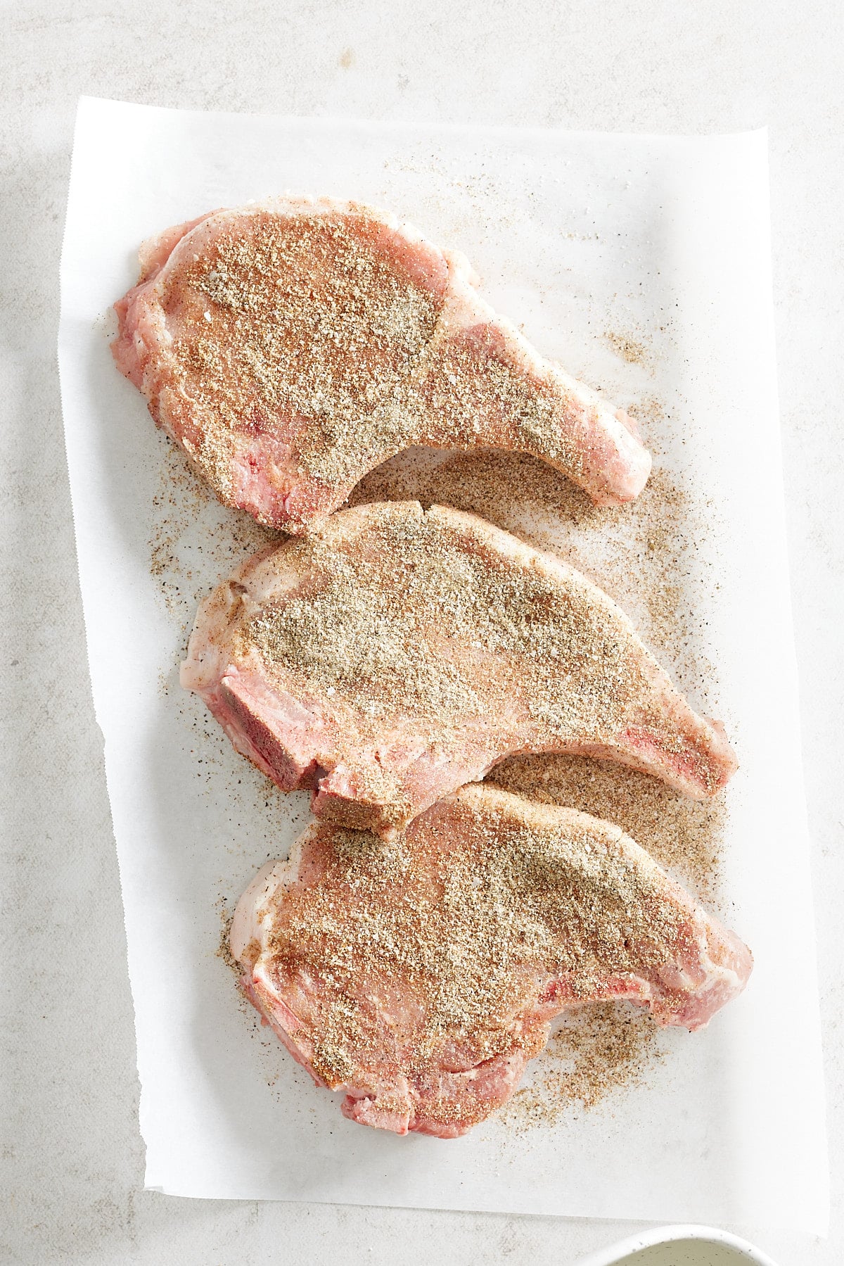 Three seasoned pork chops on a paper towel