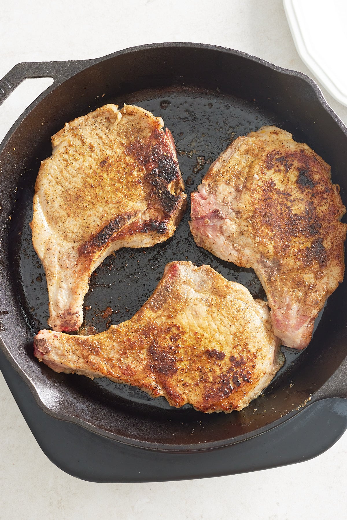 three pork chops seared in a cast iron pan