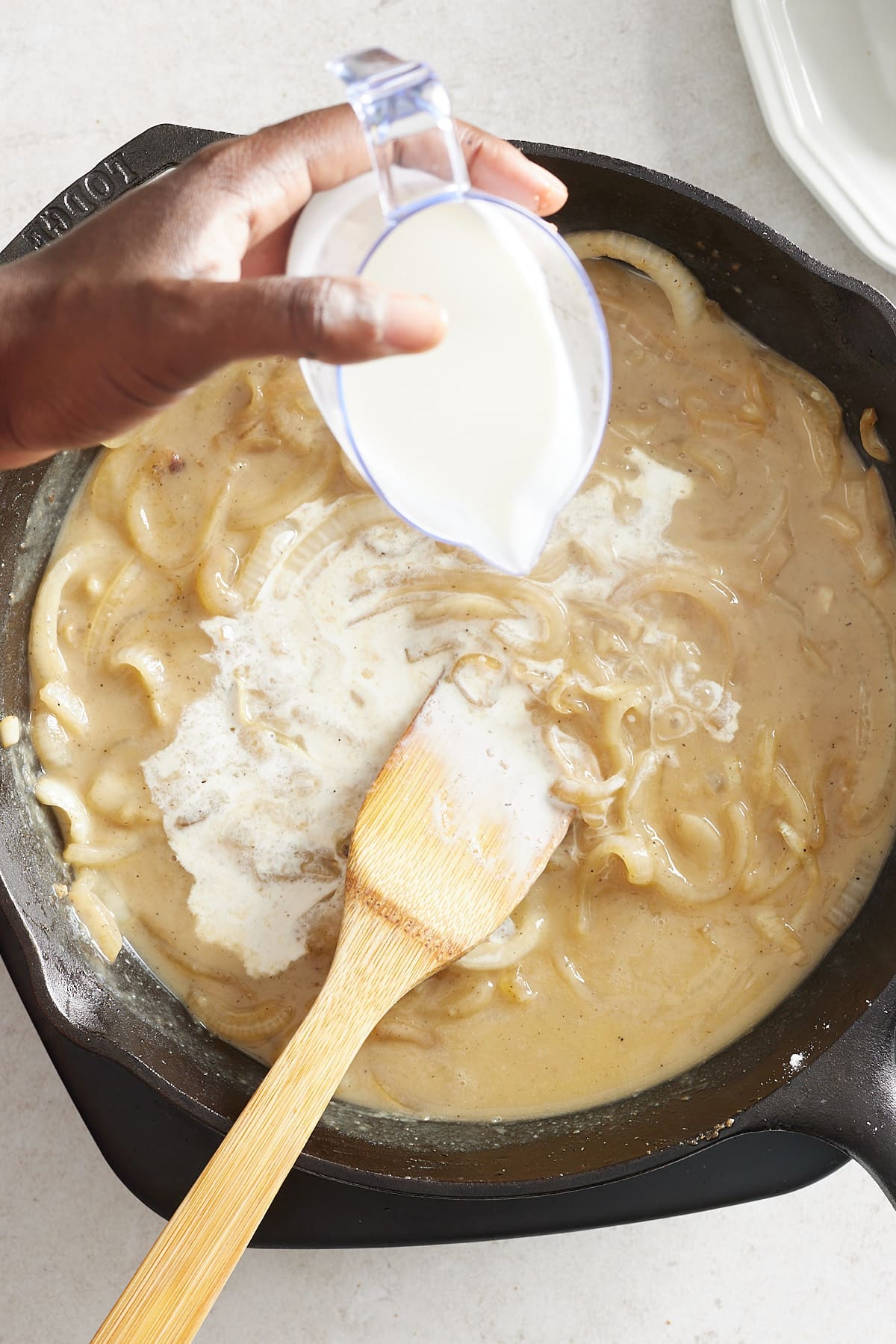 cream being added to the gravy in a cast iron pan