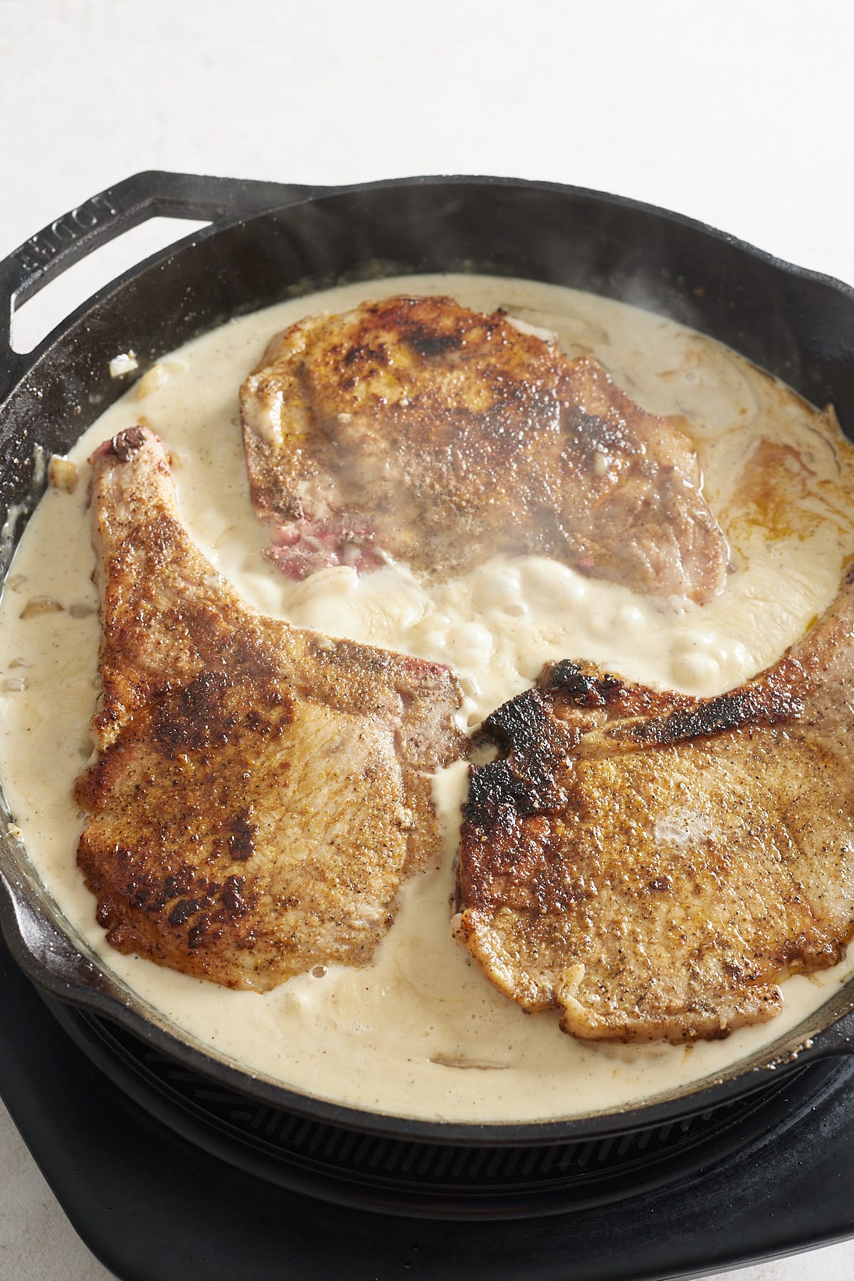 pork chops in gravy in a cast iron pan