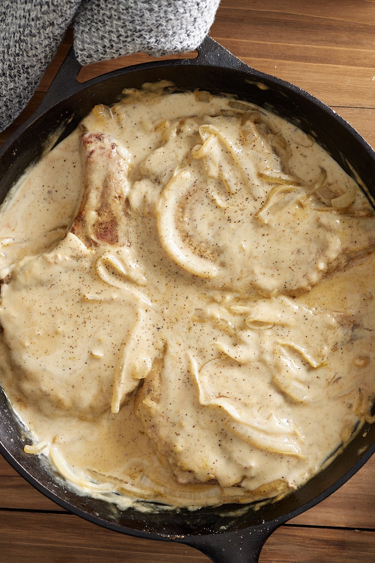 pork chops covered in gravy in a cast iron pan