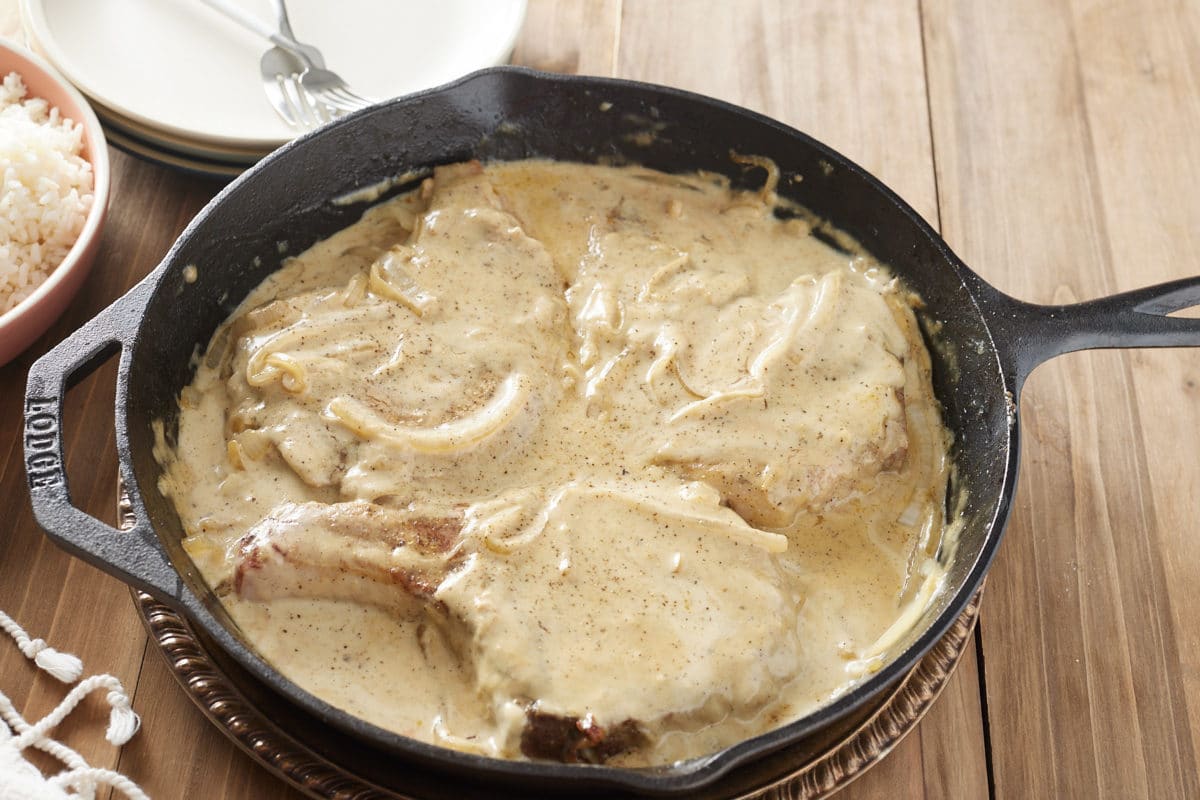 cast iron pan with three pork chops 