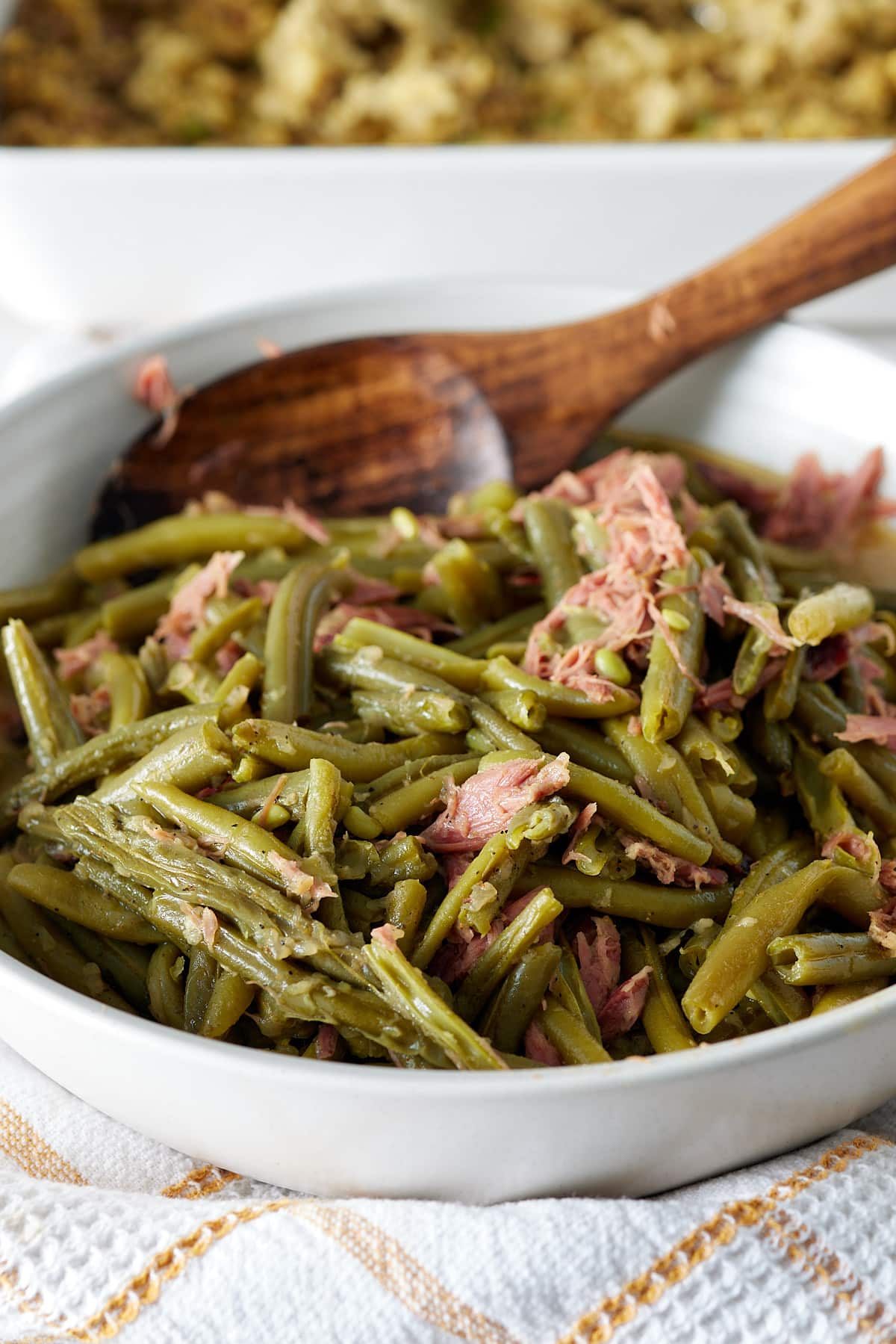 white bowl with green beans and smoked turkey with a wooden spoon