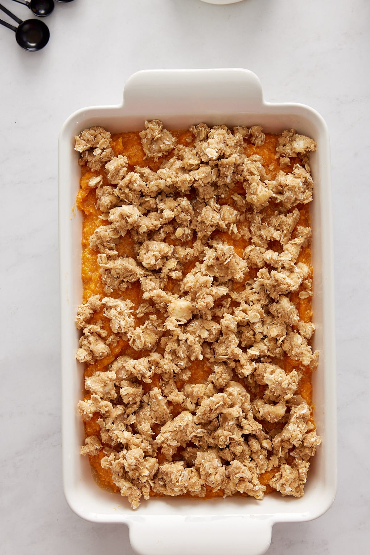 casserole sprinkled with brown sugar topping in a white casserole dish on a white background