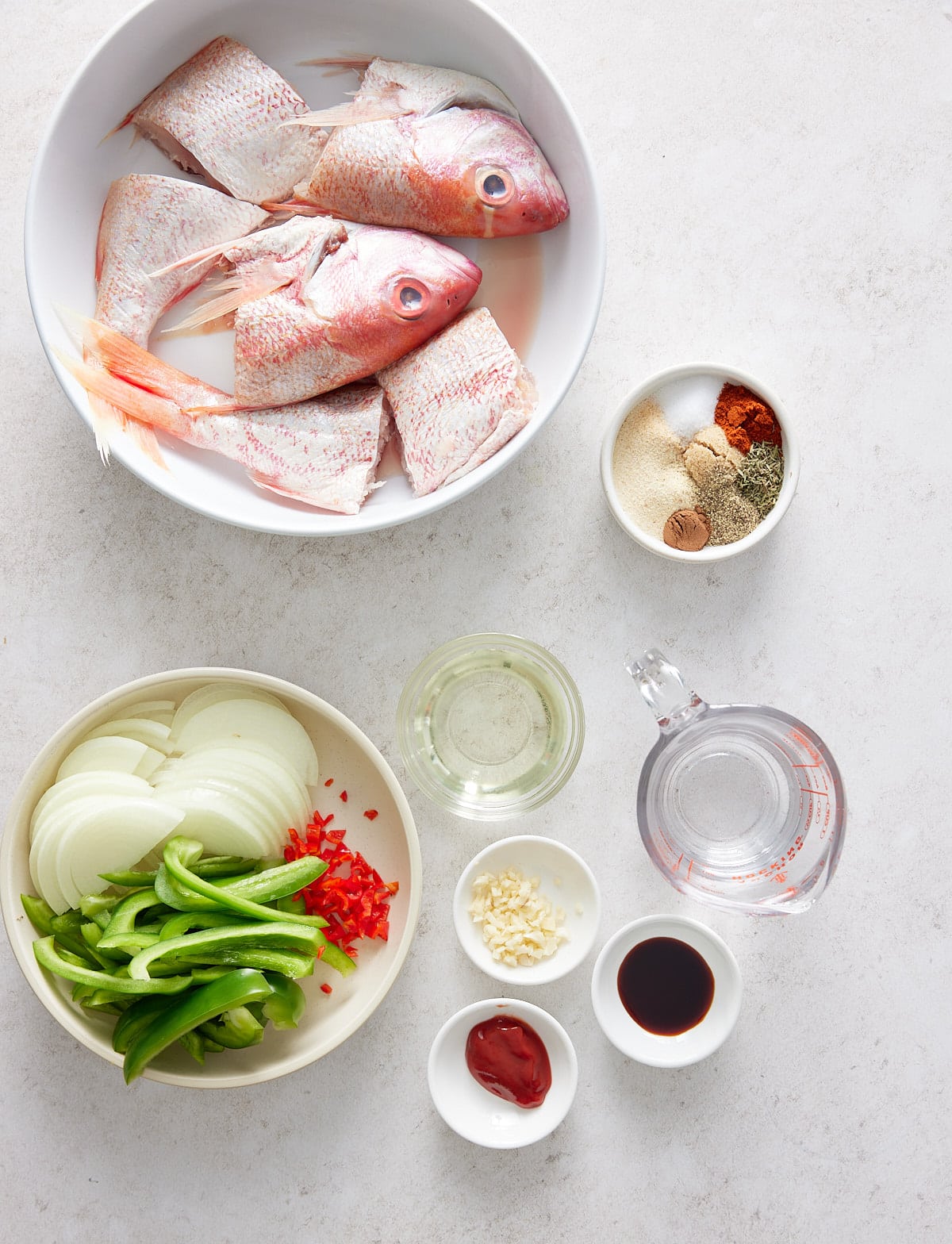 Brown stew fish recipe ingredients set out in white bowls