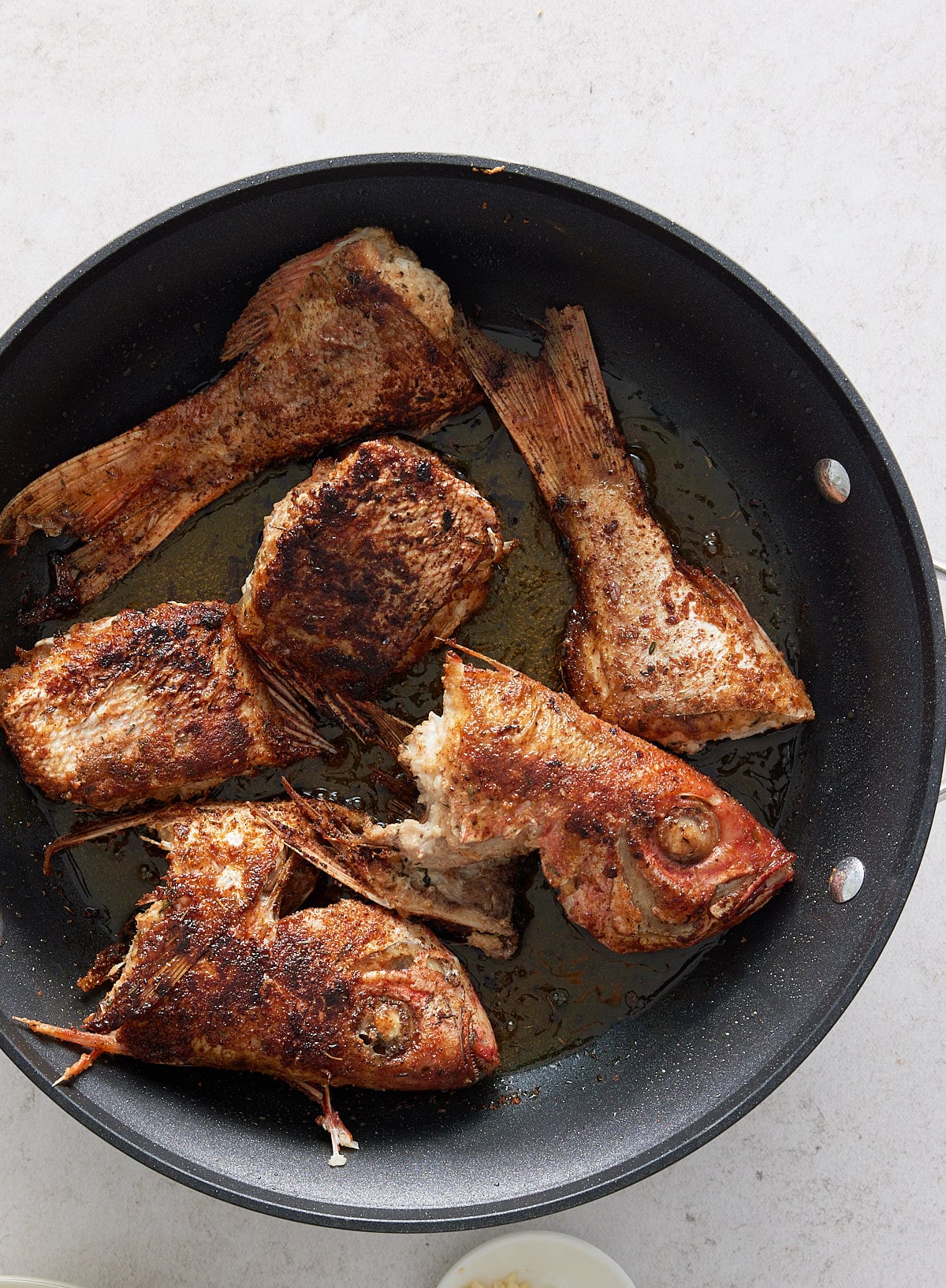 A black skillet with cooked snapper fillets