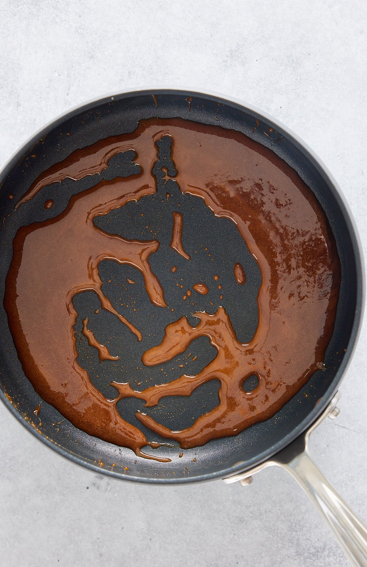 A black non-stick skillet with melted sugar and water