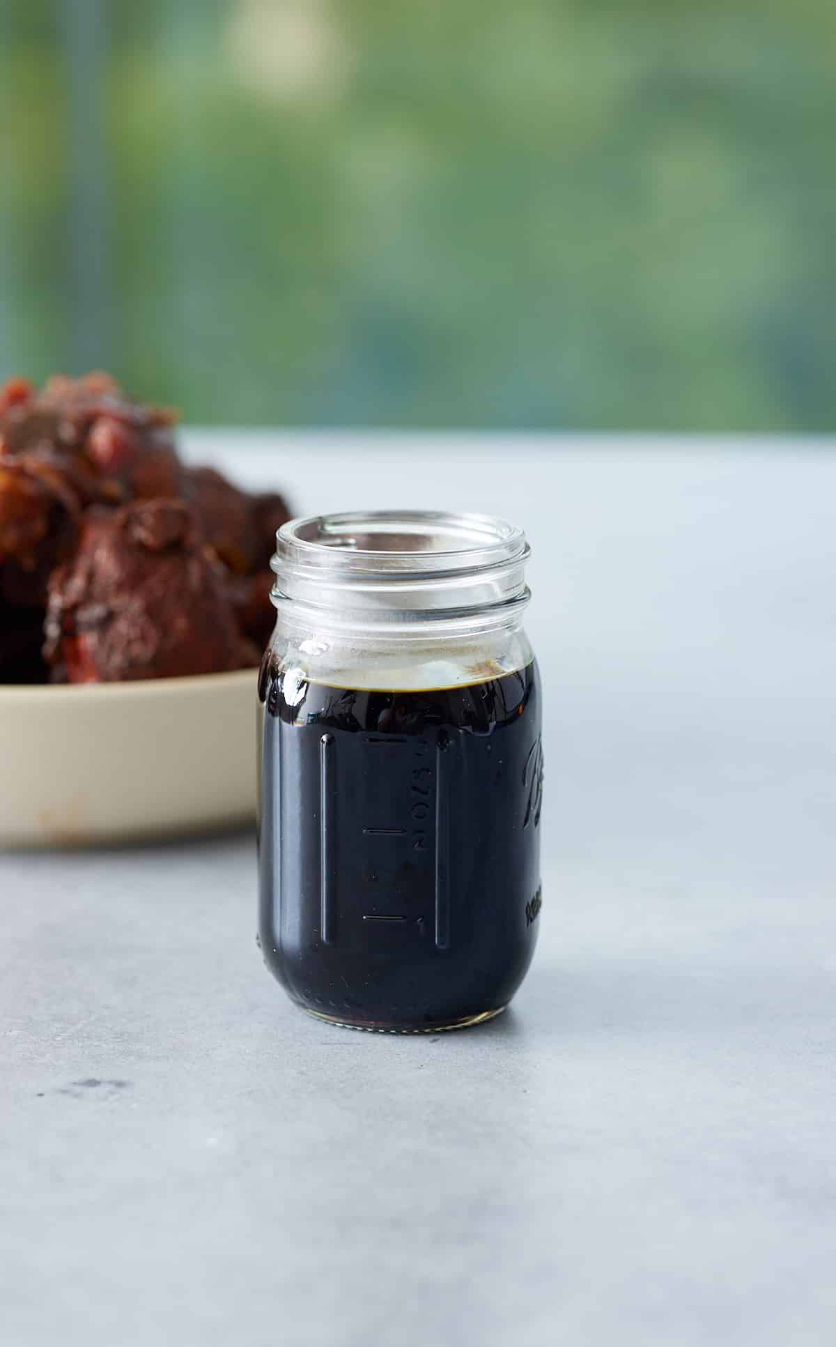 A jar filled with browning sauce set on a marble counter