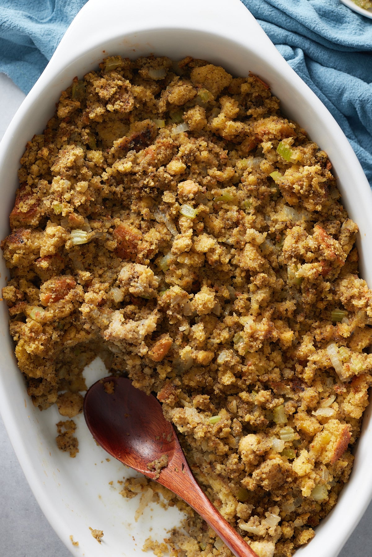 cornbread dressing scooped out of a baking dish with a wood spoon