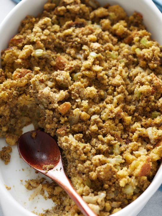 cornbread dressing scooped out of a baking dish with a wood spoon
