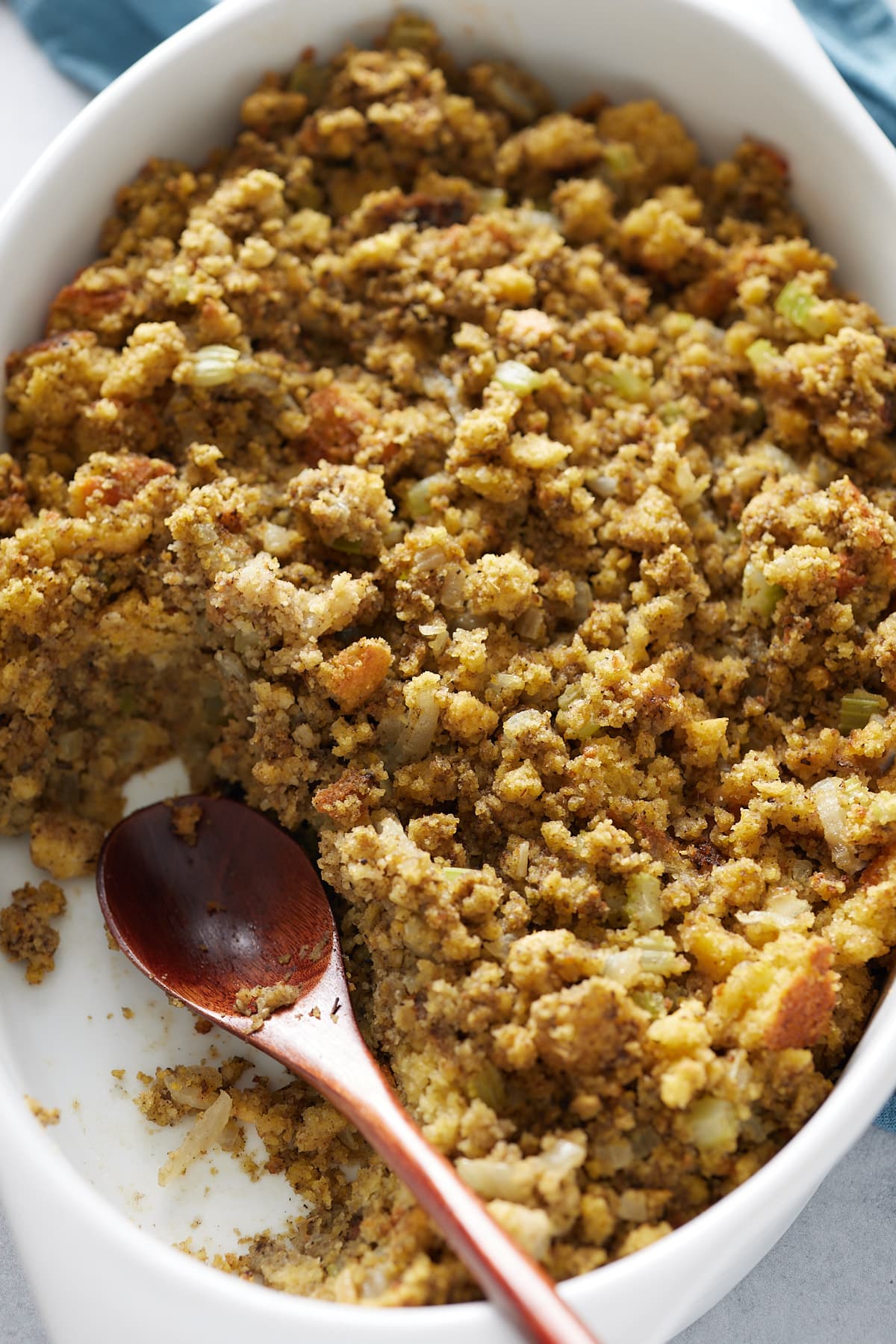 cornbread dressing scooped out of a baking dish with a wood spoon