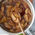 Pan with fried apples and a closeup of the apples on a wooden spoon and whole green apples set alongside