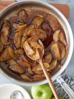 Pan with fried apples and a closeup of the apples on a wooden spoon and whole green apples set alongside