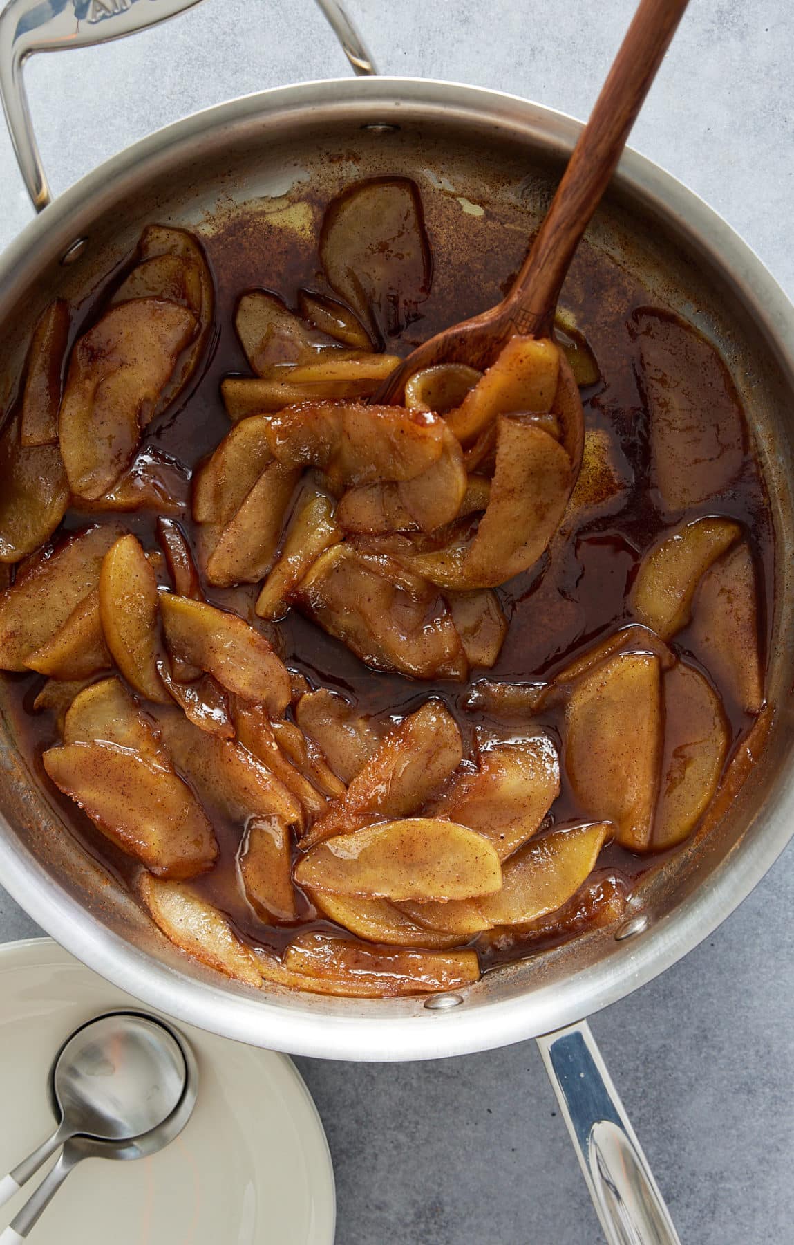 Pan with fried apples and a wooden spoon