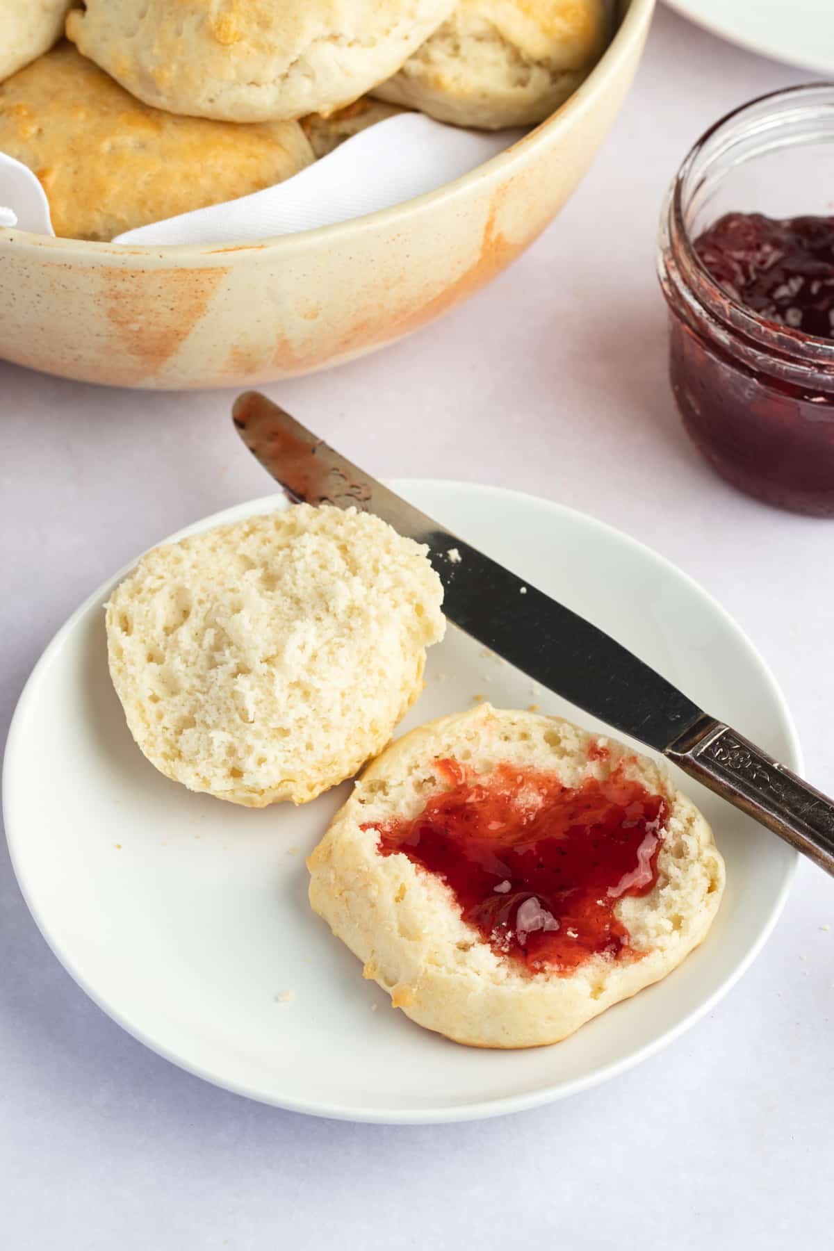 jam spread on biscuits on plate with knife on side