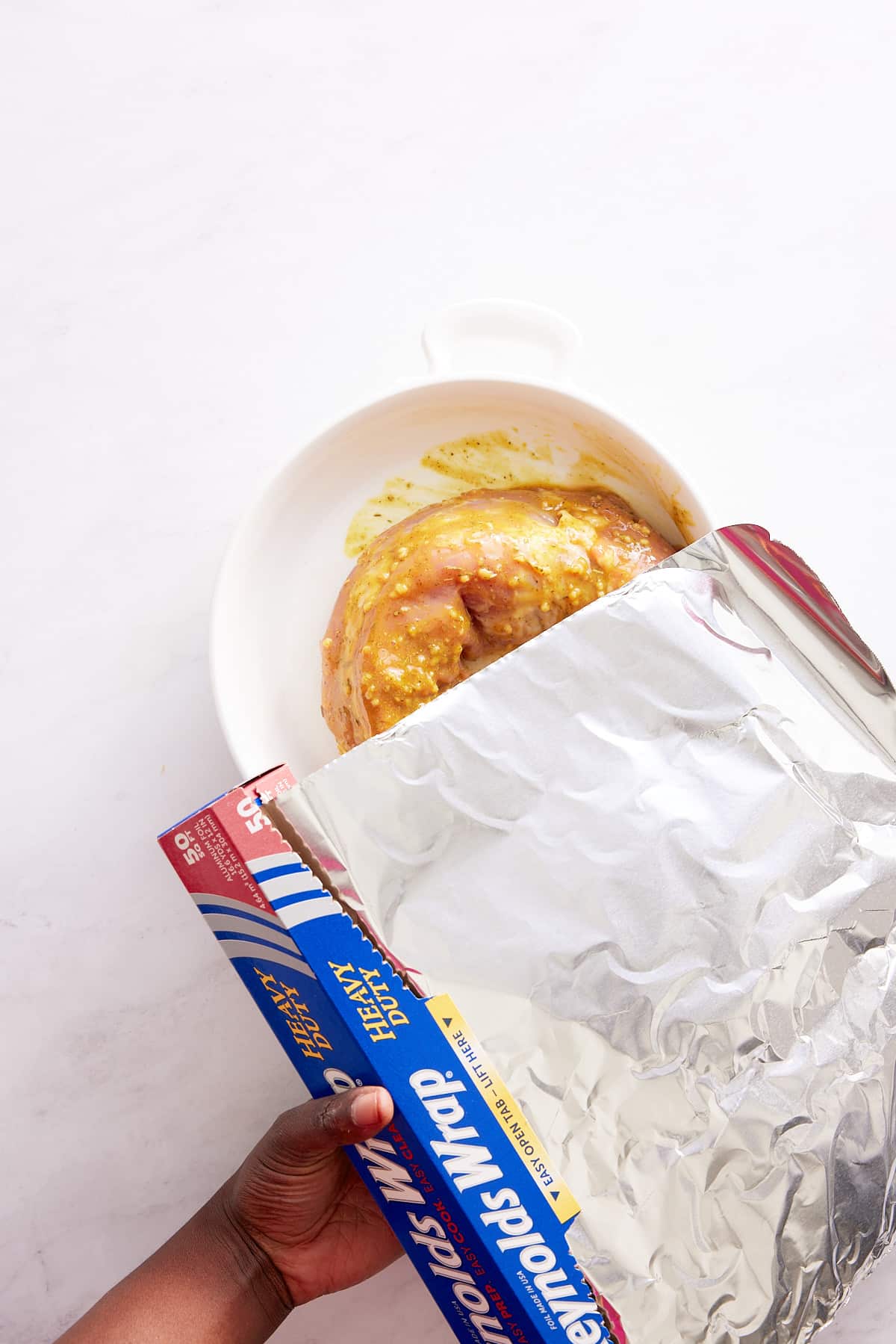 foil paper being placed over pork tenderloin