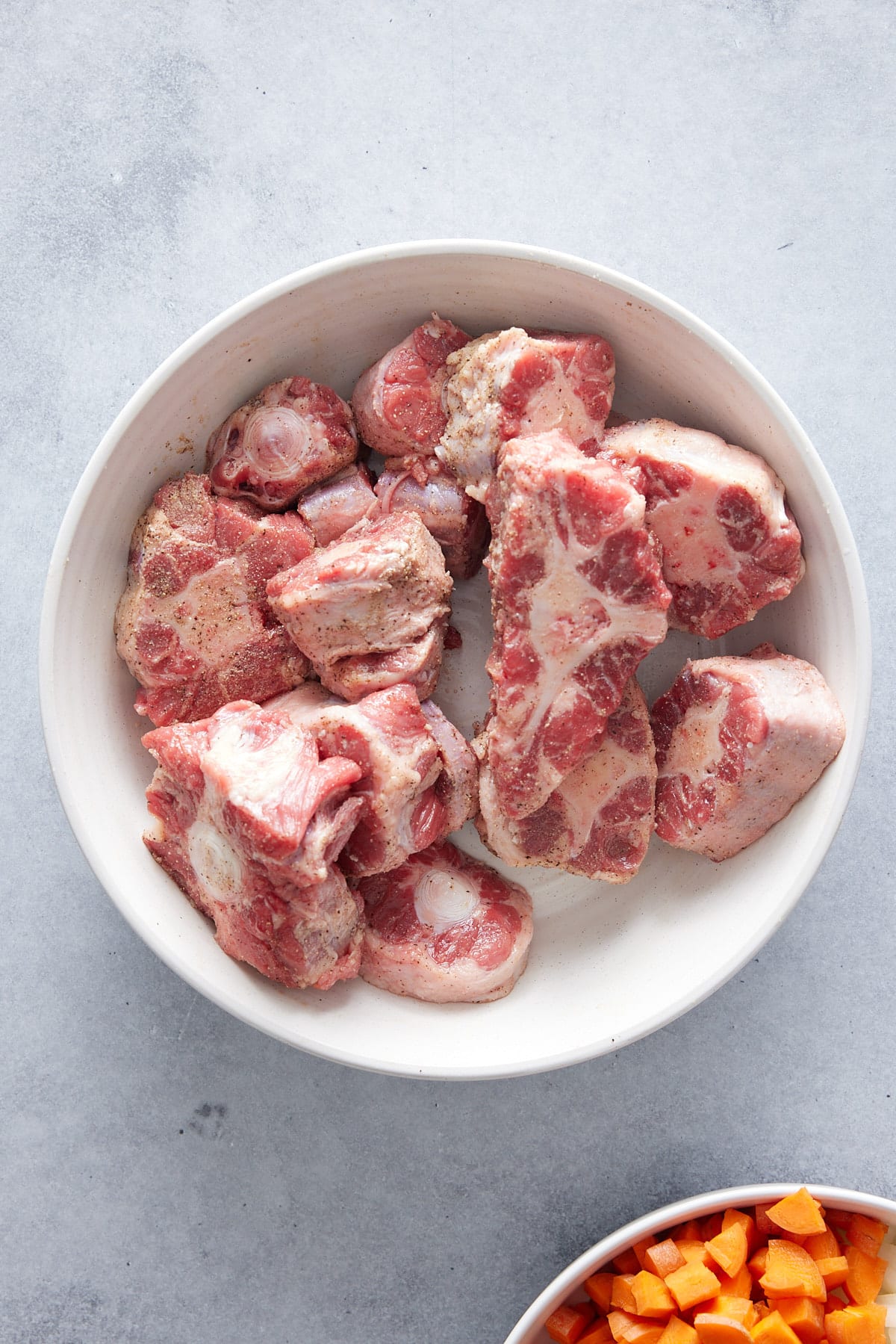 raw oxtail pieces in a large white bowl