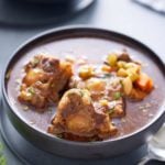 a bowl of oxtail stew on a gray background