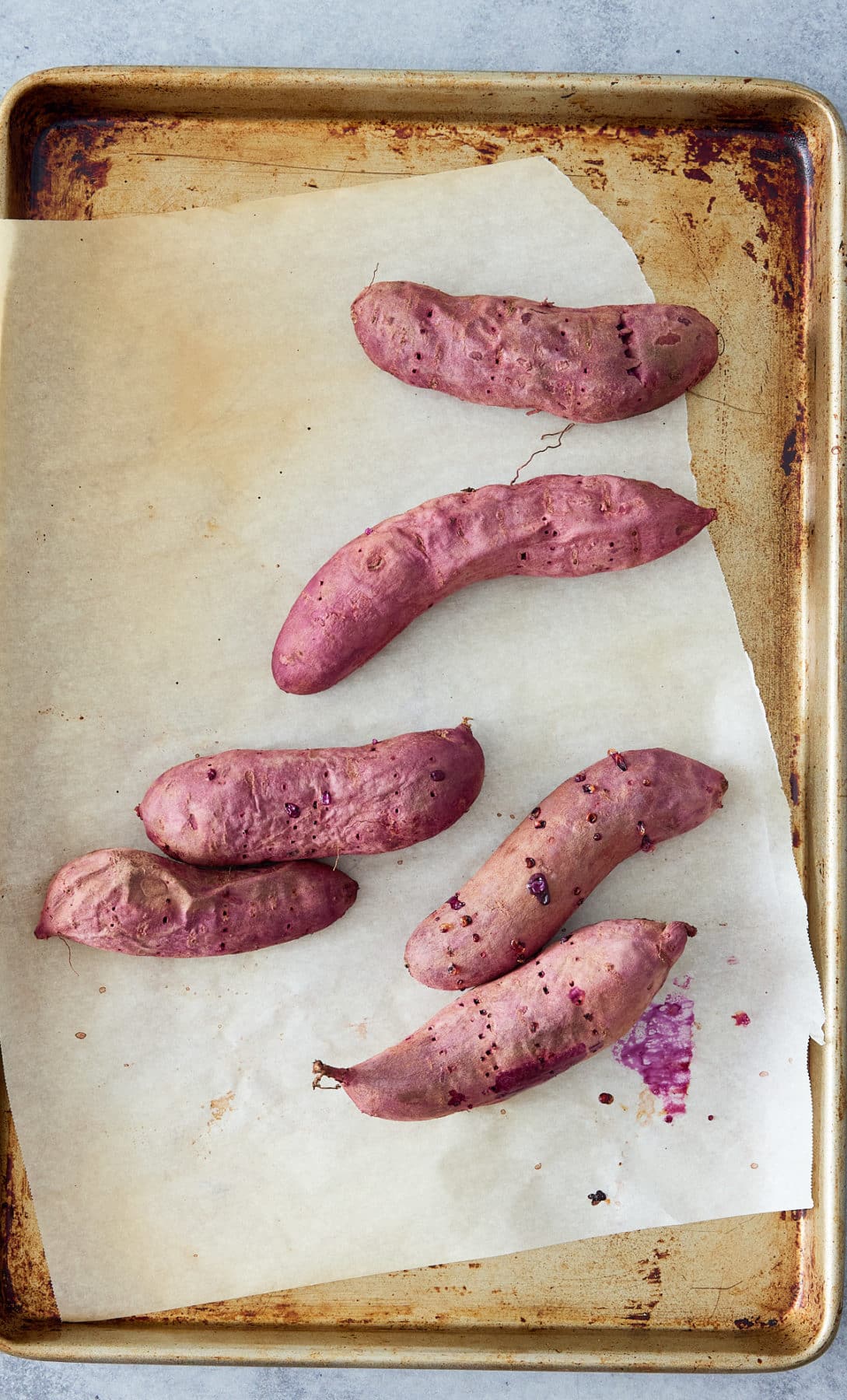 purple sweet potatos on a baking sheet with parchment paper