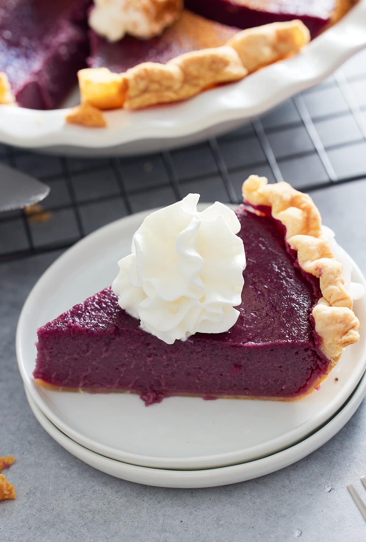 slice of purple sweet potato pie on a plate topped with whipped cream