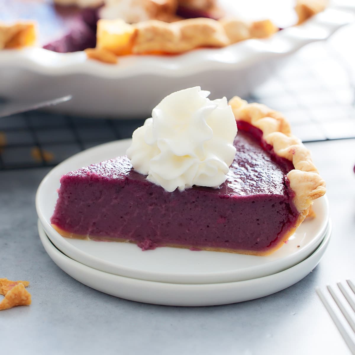 slice of purple sweet potato pie on a plate topped with whipped cream