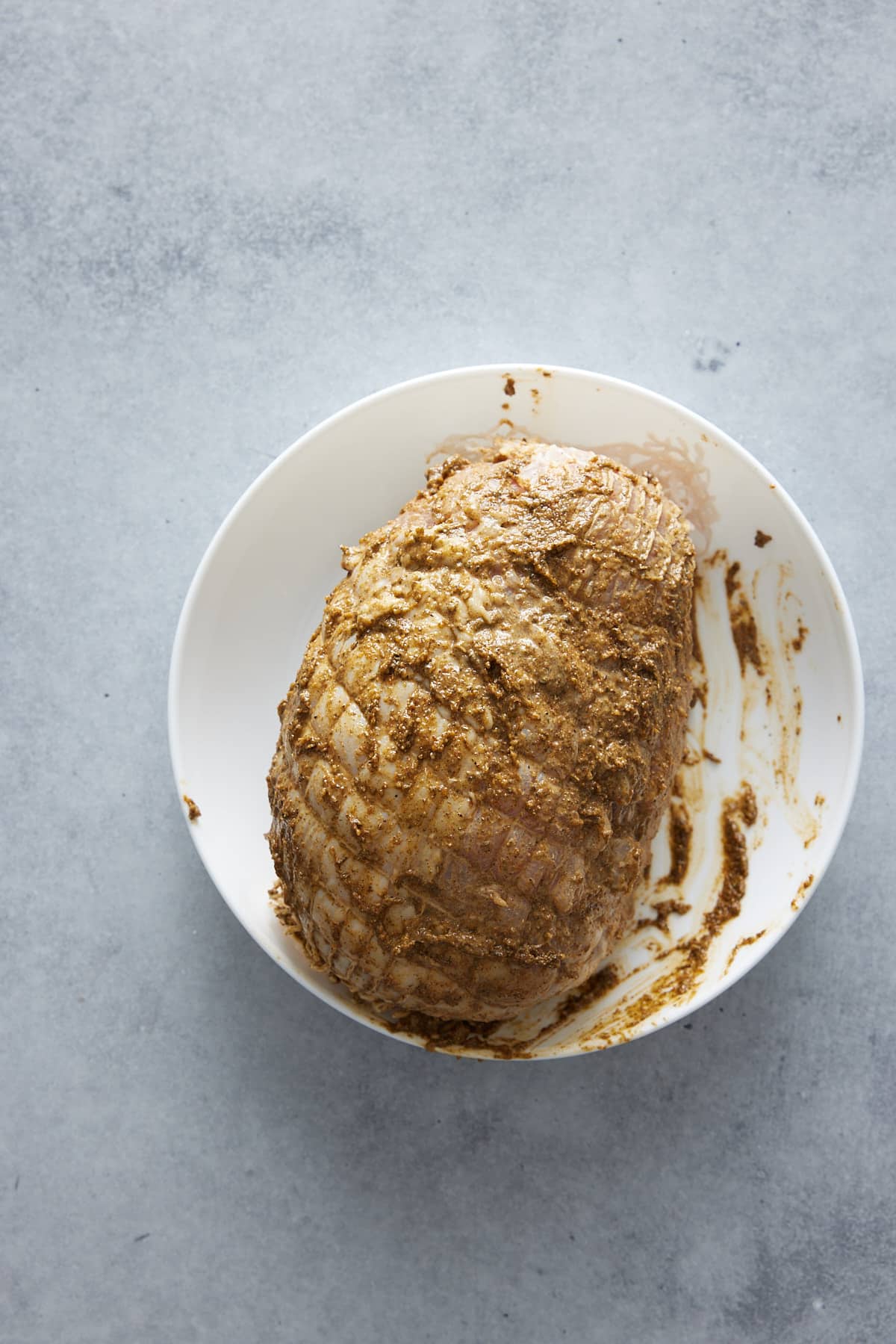 Whole turkey breast coated in spice blend set into a white bowl