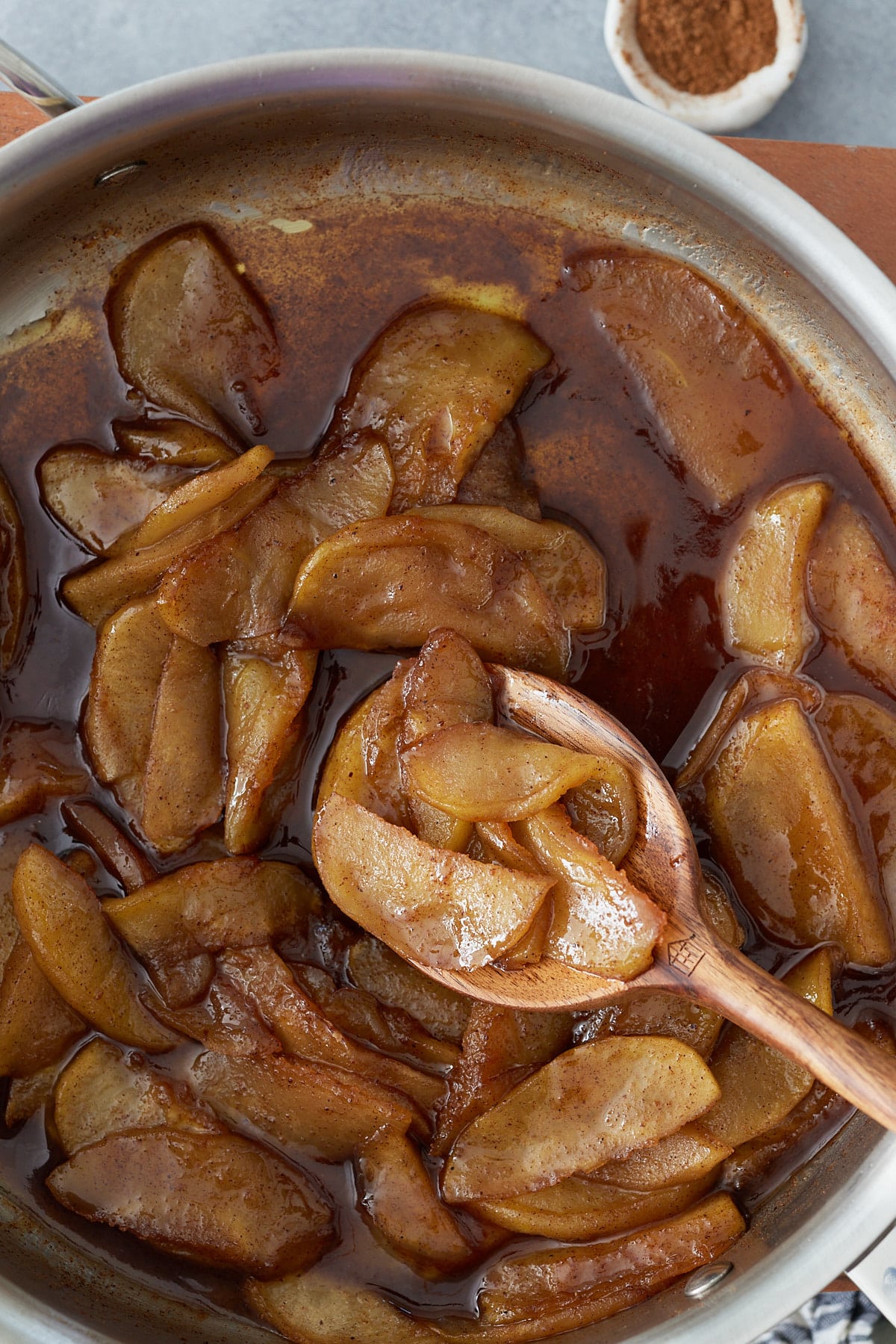 Pan with fried apples and a closeup of the apples on a wooden spoon