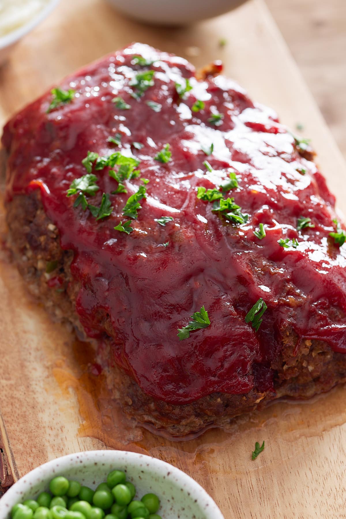 Close up image of glazed meatloaf on a wooden board