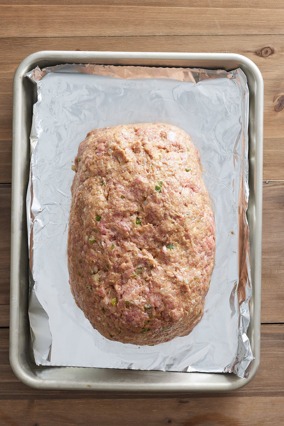 Top down image of raw meatloaf set onto a lined sheet pan ready for oven