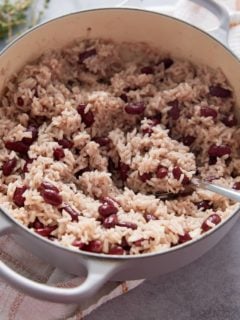 Dutch oven containing cooked Jamaican rice and peas and a serving spoon