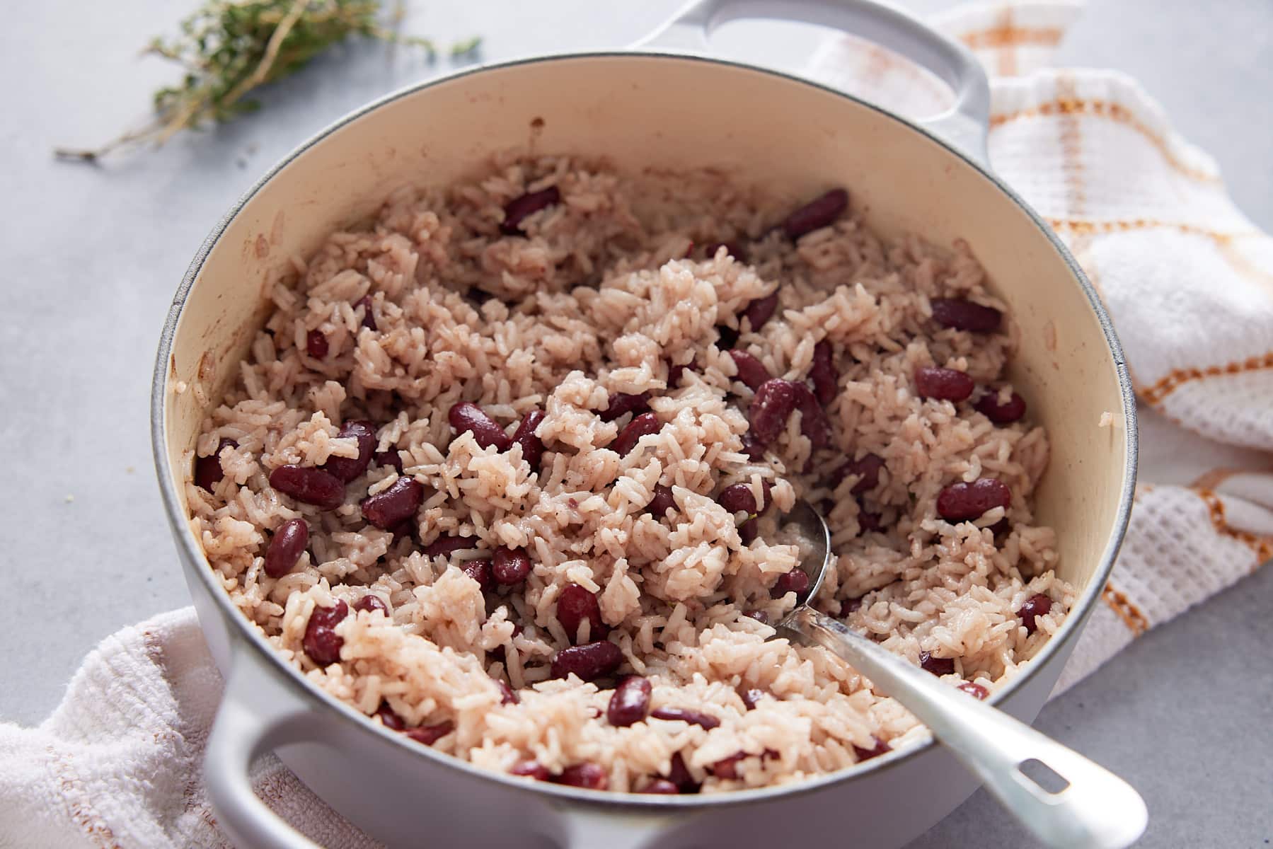 Close up image of a Dutch oven containing cooked Jamaican rice and peas and a serving spoon