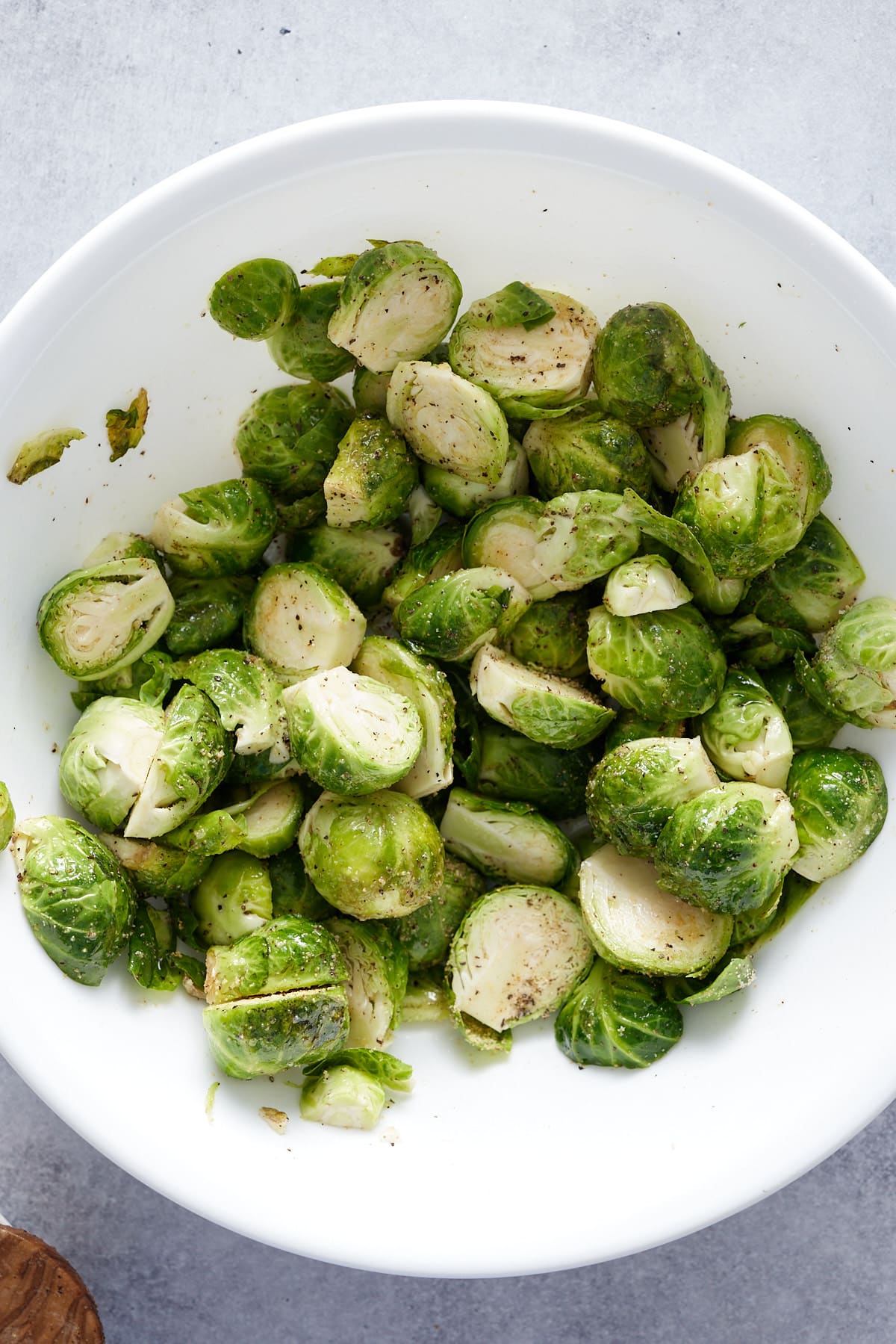 halved brussels sprouts in a bowl tossed in seasonings