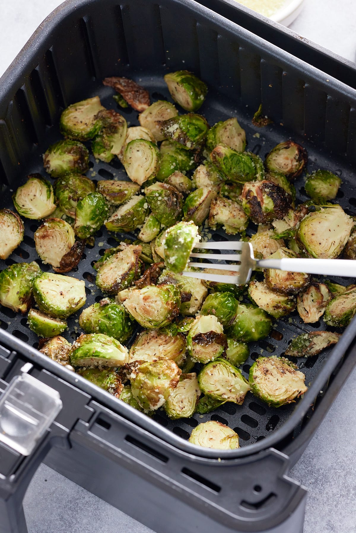 testing brussels sprouts with a fork while in the air fryer basket